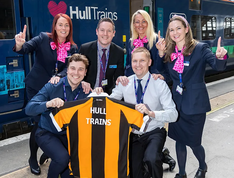 A group of Hull Trains colleagues with a Hull City shirt on the platform