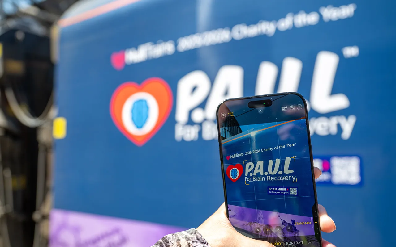 Someone taking a photo of the PAUL For Brain Recovery sticker on the Hull Trains train